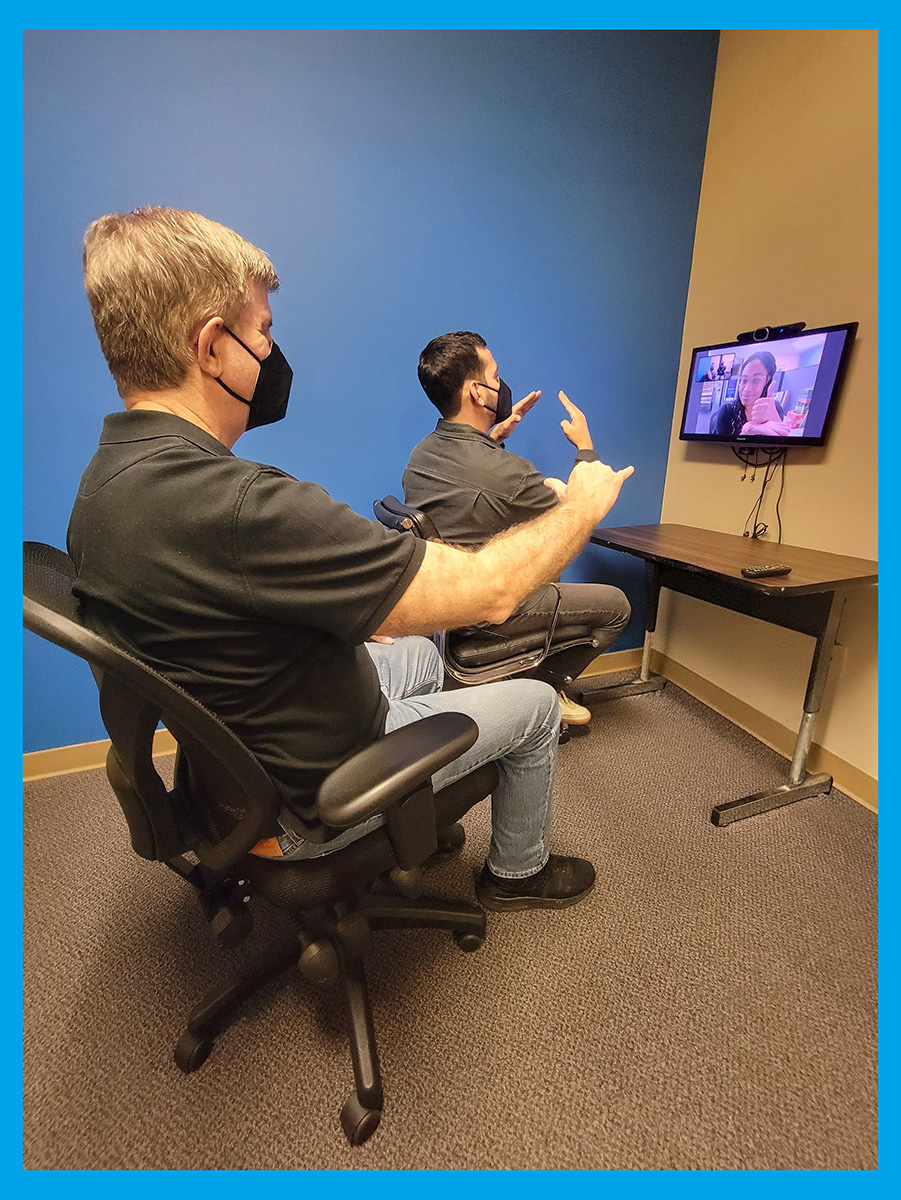 Pictured above Deaf Services Team Jet and Tobias signing inside DMC offices to Pamela on video screen to demonstrate social/soft skills plans for consumers.