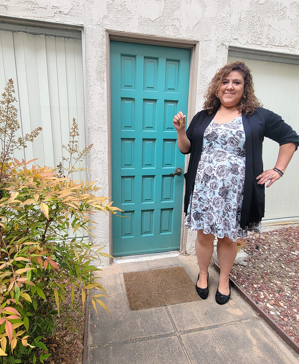Mari holding house keys in front of blue door 