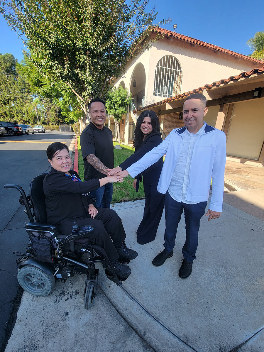 DMC Administrative Team with all hands in unity L-R: Christine Nguyen, Financial Administrator, Michael Susi, HR Generalist, Jackie Castro, Billing Administrator, and Miguel Escargaza, DMC Operations and IT Administrator