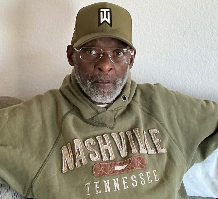 DMC Veteran Consumer Caleb T. in olive green sweatshirt and cap with glasses and grey beard