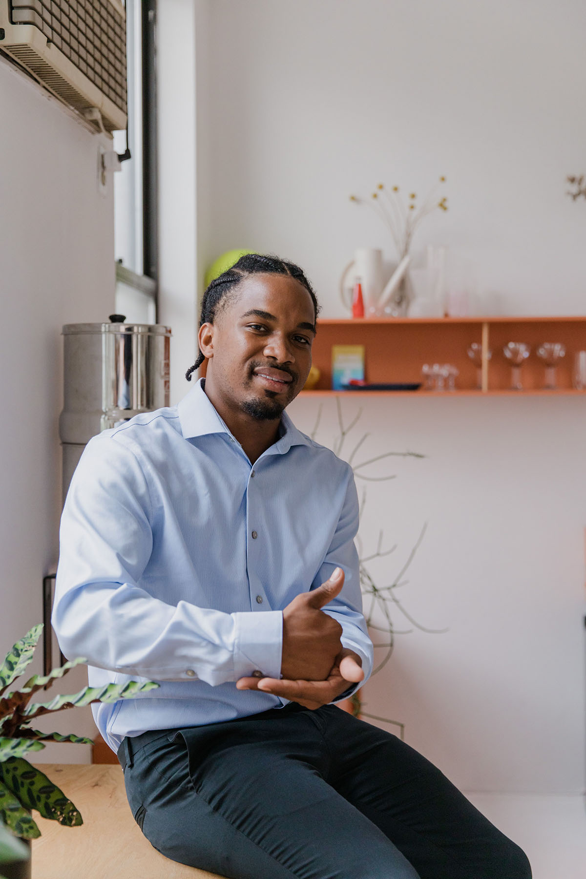 Businessman with hearing aid using sign language SIGNING "help" in ASL in a modern office space, promoting individuality and communication.