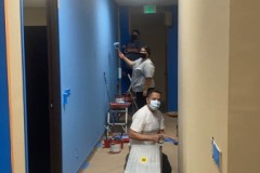 Photo-3-Hallway-painting-underway-with-Team-DMCs-Miguel-Judith-and-Esme-Painting-in-progress.-Left-wall-is-in-blue-as-team-members-are-in-hallway