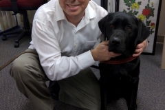 DMC staff Paul at ground level posing with his guide dog