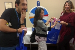 Guests with silly expression at prize wheel, staffed by Grace