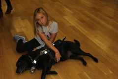Young girl petting guide dog Ninya both on wood floor