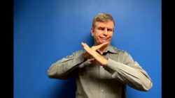 Man in grey shirt making a timeout gesture.