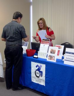 Community Services Outreach picture of staff member and participant at DMC resource table.