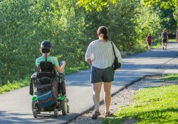 Independent Living Skills Instruction consumer in power chair with Instructor walking beside.