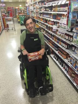 Man in wheelchair stocking shelves at grocery store Employment Assistance