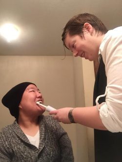 PAS Attendent helping a young adult female brush her teeth.