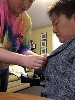 PAS Attendent helping young adult female button her sweater.