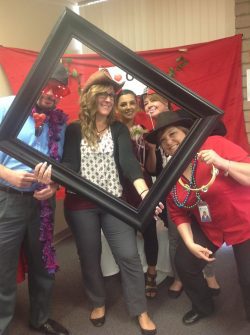 Several staff with props posing for photo booth picture during I Heart OC event. DMC connect