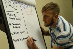 Youth writing pros and cons of socializing during lunch