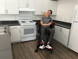 Man in wheelchair smiling in kitchen.