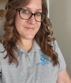 Woman in gray shirt with logo.