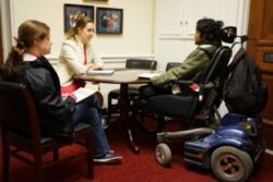 Three people sitting around a table, one in a wheelchair.