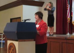 Woman speaking at podium with microphone.
