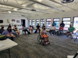 A photo of youth and staff sitting in a circle with one youth in the middle, using a manual wheelchair.