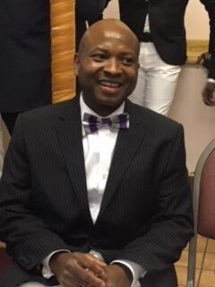 Rodney Hume- Dawson is pictured sitting. He is wearing a tuxedo and bow-tie, smiling.