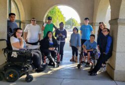 Youth Program team and participants gathered together outside in the arches of the IL Center, smiling in unity