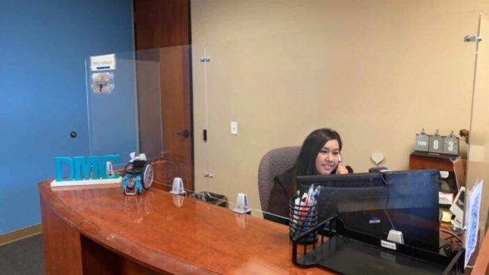 A photo of a person answering the phone while seated at the reception desk.