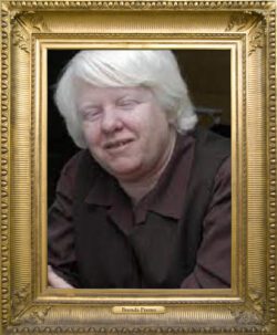 Pictured, Brenda Premo wearing a brown collared blouse and vest, smiling softly.
