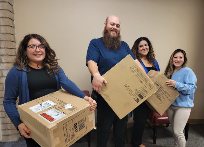 DMC Housing Team smiling, holding moving boxes