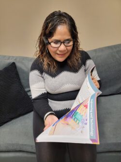 Pictured, Person sitting with Orcam technology being used to read book
