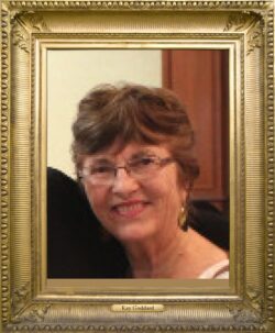 Pictured, Kay Goddard with short medium brown hair, wearing glasses and dangle earrings, smiling