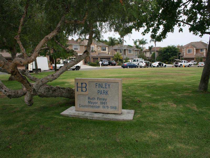 Pictured a large tree and a concrete marker for Huntington Beach’s Finley Park named after Ruth Finley