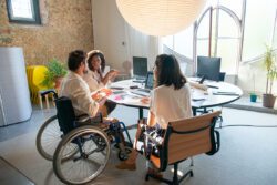Three people gathered around a table using technology