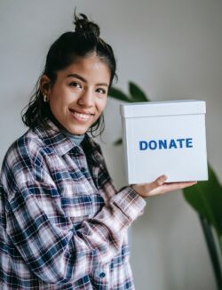 Pictured, Person in plaid shirt holding donation box.