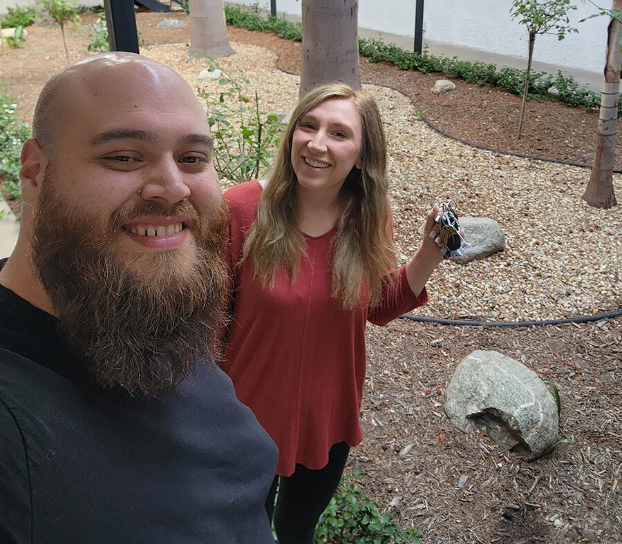 Happy consumer smiling with DMC Housing rep in garden with trees surrounding in the background.