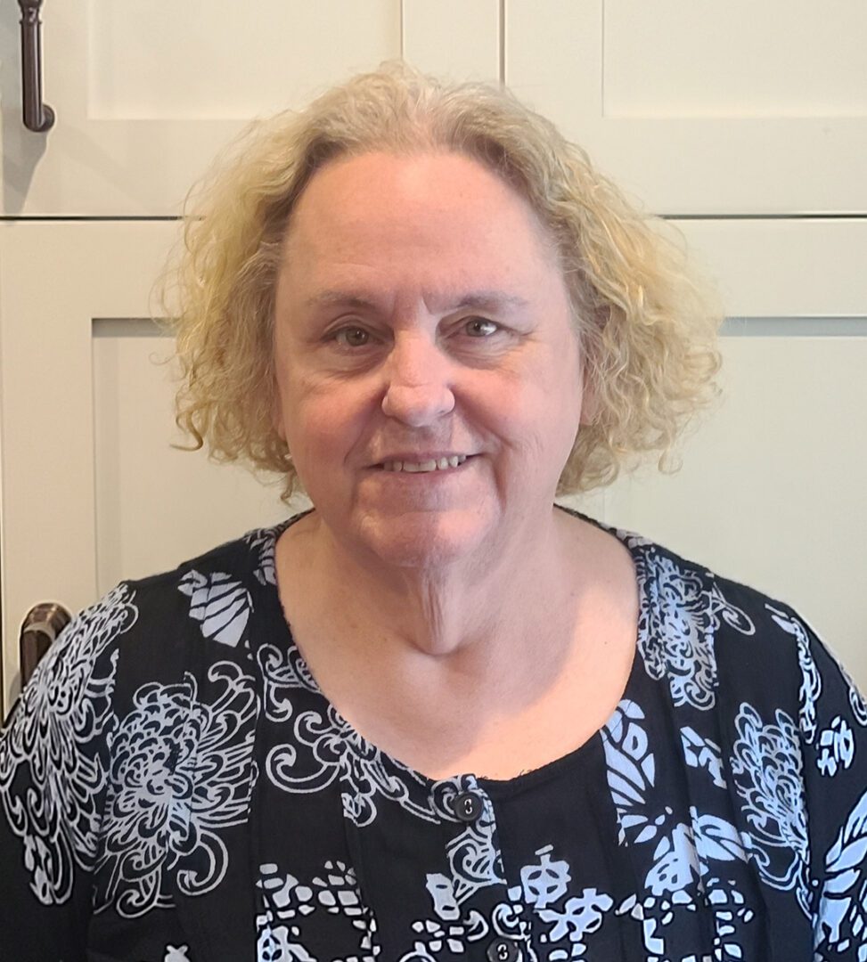 Pictured, DMC's Secretary, Katy Wright, smiling wearing a black and white blouse.