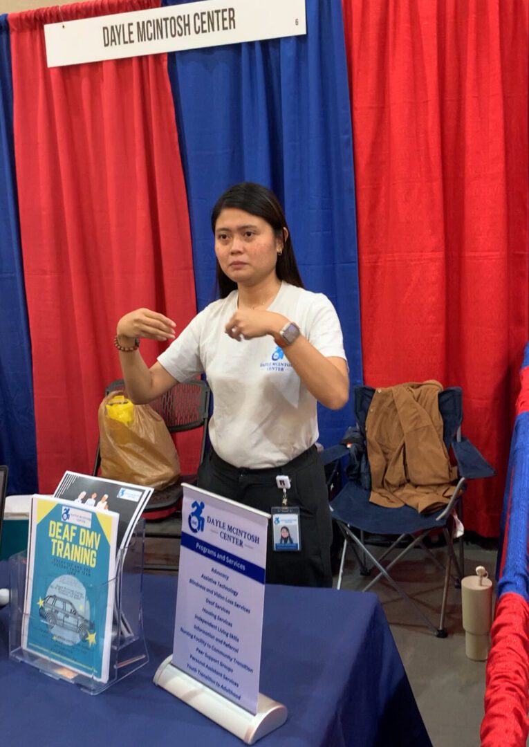 Pictured, DMC Deaf Housing Coordinator Doryna at Deaf Nation Conference signing at booth.