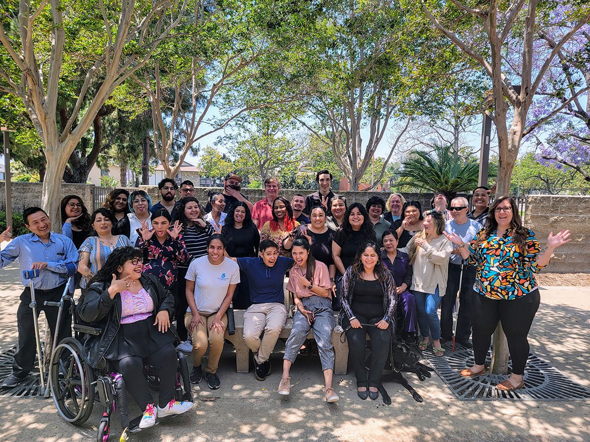 A silly group photo of our entire DMC team, give or take a few. We are outside on a sunny day during our annual team celebration. 