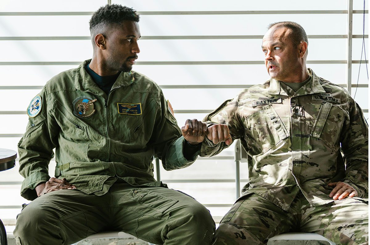 Two military veterans seated fist bumping in unity.