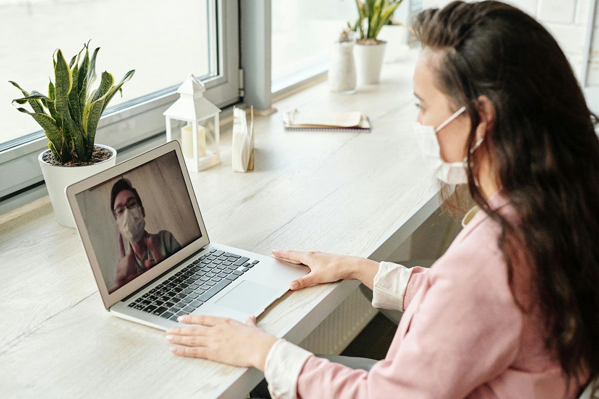 Person getting telemedicine support online. Individuals are masked talking on a computer.