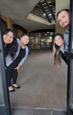 Pictured, DMC’s ADRC Team smiling while peeking heads around an open doorway with doors behind them.