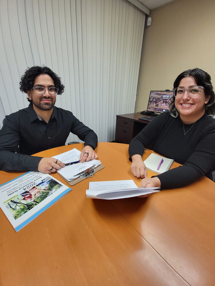 Pictured Community Transitions Team Babar and Christabel doing transitions paperwork seated at desk, smiling