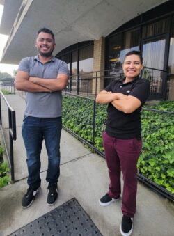 Pictured Ivan, Lead Home Access Specialist and Ana, Medi-Cal Home Access Specialist standing on access ramp outside of DMC smiling with fierce determination and support to advocate for individuals in need of Home Access modifications.