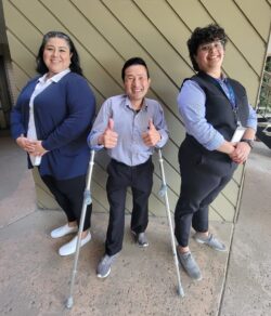 a picture of the Personal Assistant Services Team in front of a pillar. They are smiling and/or giving a thumbs up.