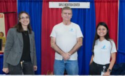 DMC Team and volunteers smiling in front of the DMC booth at Deaf Nation Expo.