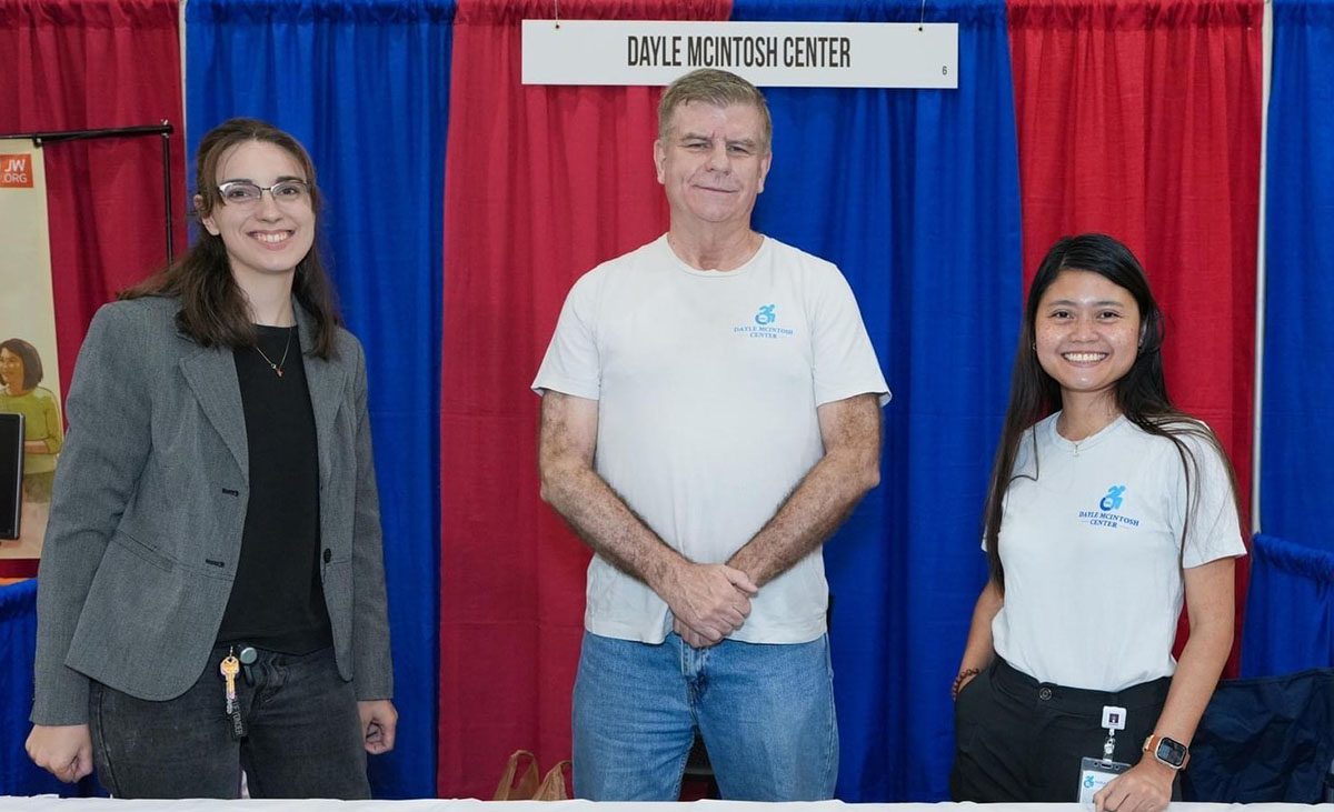 DMC Team and volunteers smiling in front of the DMC booth at Deaf Nation Expo. 