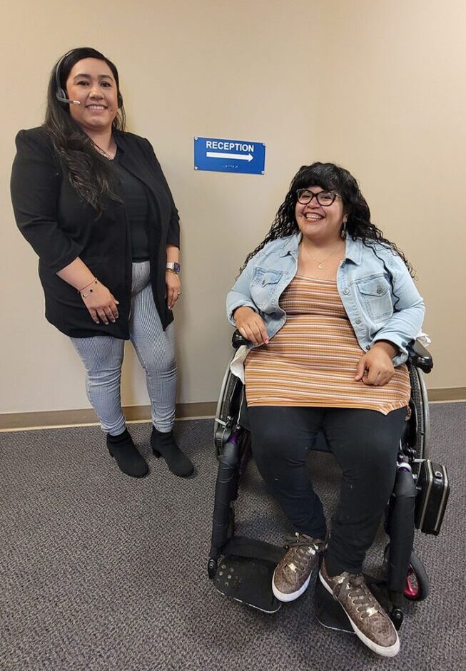 Pictured:  Nelly Gomez, DMC’s Lead Youth and Information Coordinator, smiling in front of a blue reception sign on the wall; Left, pictured is Bianca Cerrillo, DMC’s Receptionist/Information and Referral Coordinator answering a call on a phone headset.