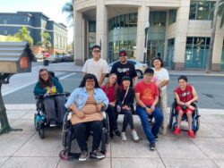 DMC Youth Connect outing with Youth Services Team members Nelly, Alan and Volunteer Youth Advisor, Mona. Everyone is outside smiling on the sidewalk of an intersection with building behind the group.