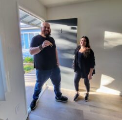 Pictured DMC’s Housing Team Adam and Lizeth in doorway of an apartment numbered “4.” Adam is holding house keys, both are smiling