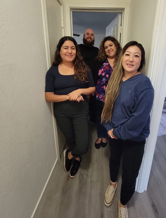 Pictured DMC Housing Team Lizeth, Adam, Marisol and Ruth in hallway of prospective consumer apartment. 