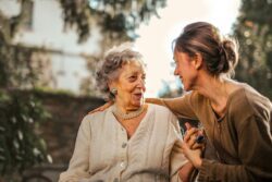 Pictured Younger adult showing compassion and care to community member older adult seated outside.