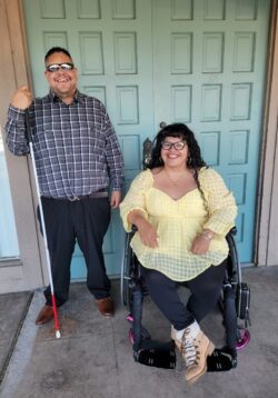 Pictured DMC’s Youth Transition Services Team from DMC Youth Connect – Alan on the left in a blue plaid shirt and Nelly on the right wearing a yellow blouse. Both are smiling outside in front of a set of double green doors.